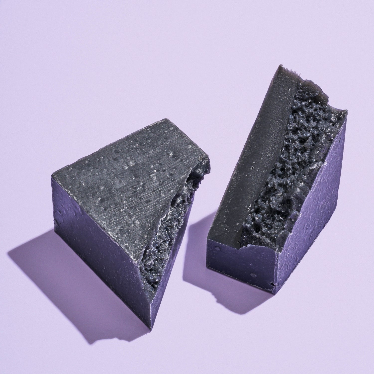 Bamboo Charcoal Detox Soap Bar split into two pieces against purple background